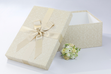 Die BrautkleidboxBeige Labyrinth wird mit einer passenden beigen Satinschleife komplettiert.